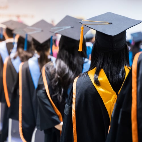 College graduates standing in line wearing their caps and gowns